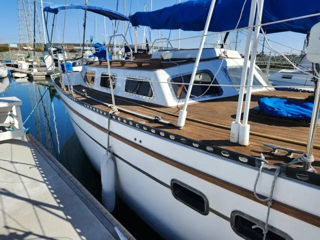 Slide: The Image of 1982 Custom King's Legend 41 sailboat docked in marina, featuring wooden deck and blue canopy. - 49