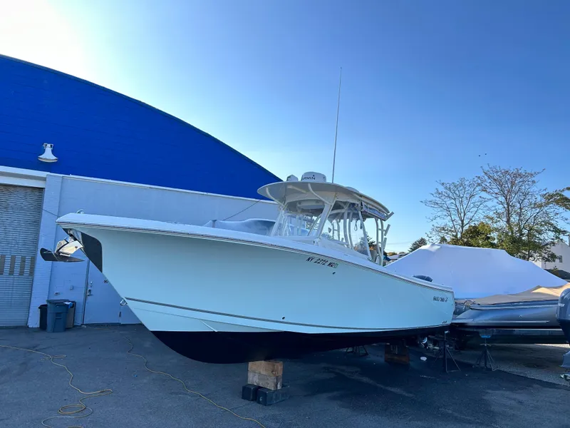 The Image of 2018 Sailfish 290 CC boat on display outdoors near a blue building. - 0