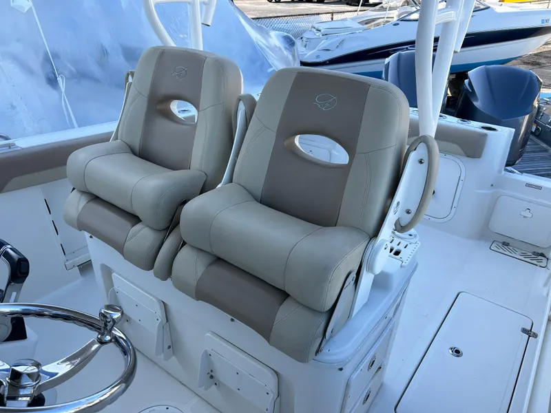 Slide: The Image of 2018 Sailfish 290 CC boat with dual cushioned helm seats and steering wheel. - 10
