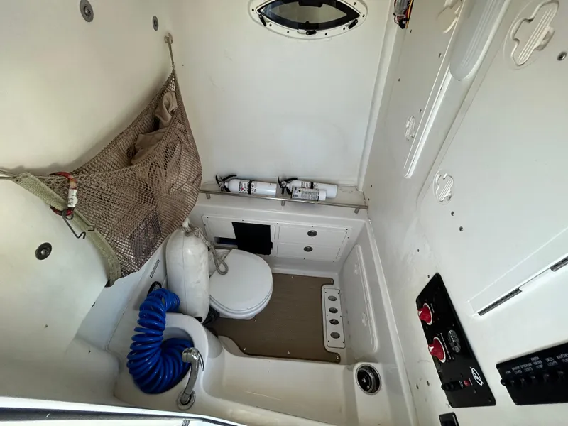 Slide: The Image of 2018 Sailfish 290 CC boat interior with toilet, storage net, and control panel. - 13
