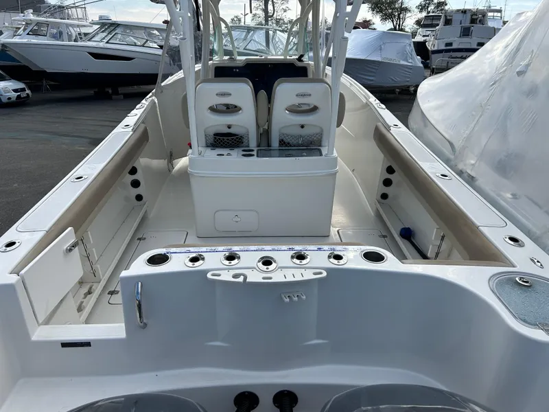 Slide: The Image of 2018 Sailfish 290 CC boat interior with seating and storage, docked among other boats. - 18