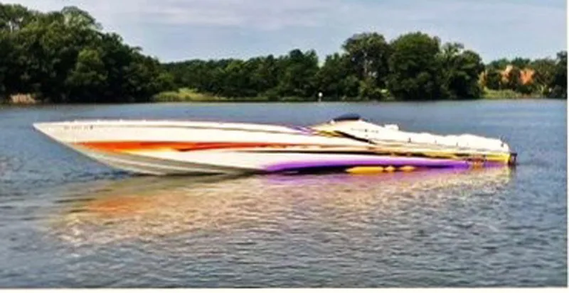 Slide: The Image of 2001 Cigarette 46 Rough Rider boat on a calm lake with trees in the background. - 3