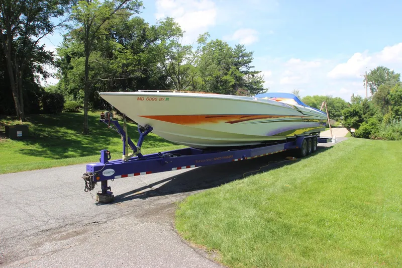 Slide: The Image of 2001 Cigarette 46 Rough Rider boat on trailer, parked on a sunny road. - 39