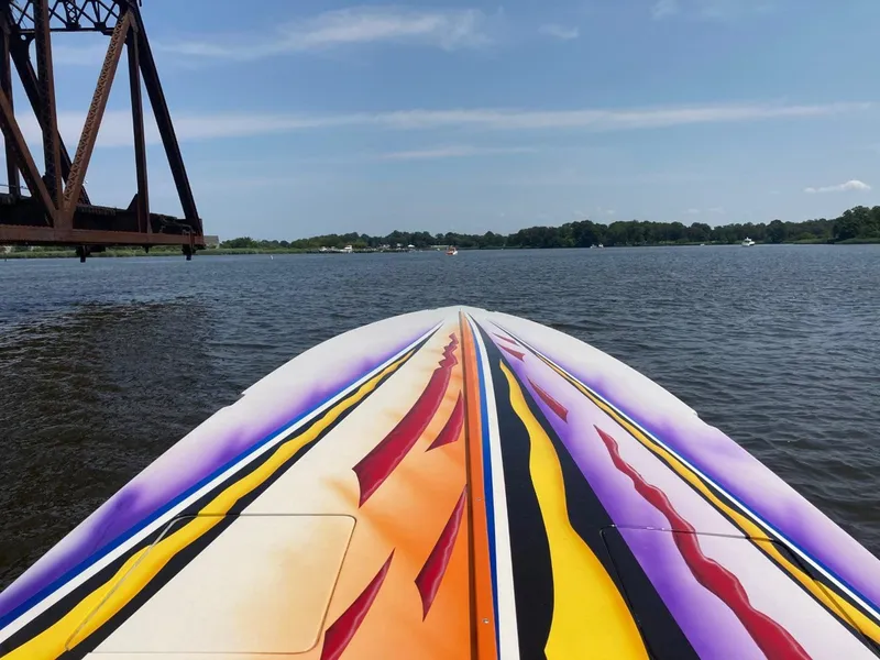 Slide: The Image of Colorful 2001 Cigarette 46 Rough Rider boat on a calm lake under a clear sky. - 8