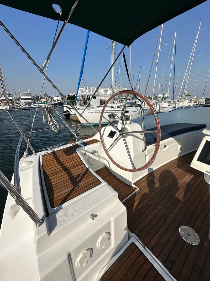 Slide: The Image of 2011 Beneteau Oceanis 40 sailboat cockpit with wooden deck and steering wheel in marina. - 32
