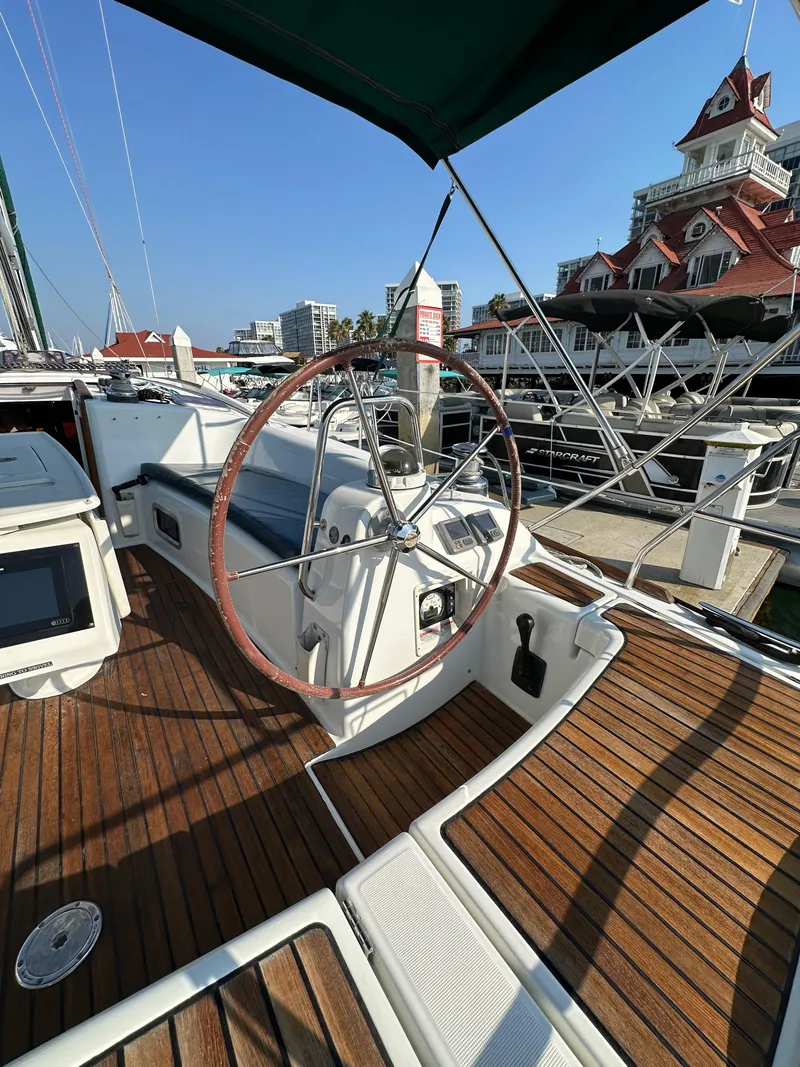 Slide: The Image of Beneteau Oceanis 40 sailboat, 2011 model, docked with wooden deck and steering wheel visible. - 33