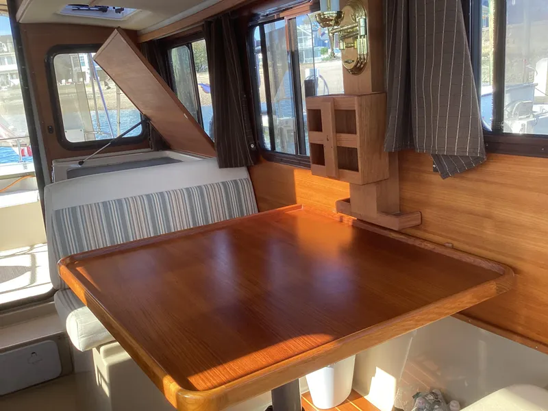 Slide: The Image of Interior of 2012 Ranger Tugs R-27 with wooden table and striped seating. - 20
