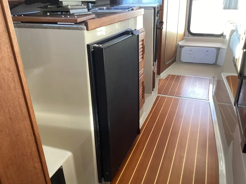 Slide: The Image of Interior of 2012 Ranger Tugs R-27 with wood flooring and compact kitchen area. - 21