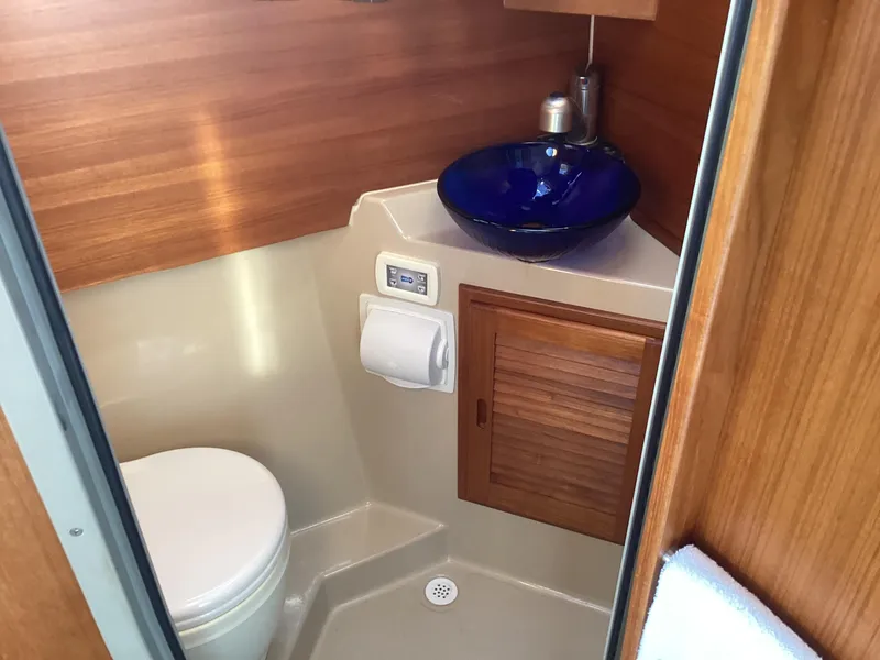 Slide: The Image of 2012 Ranger Tugs R-27 boat bathroom with wooden cabinetry and blue glass sink. - 34