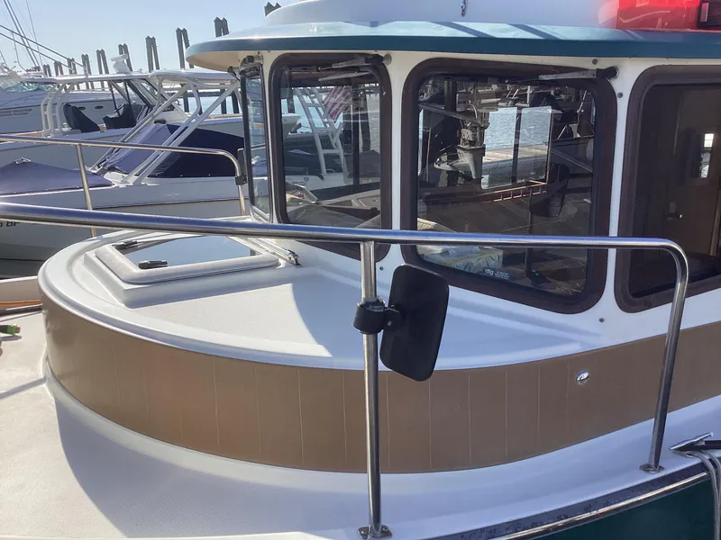 Slide: The Image of 2012 Ranger Tugs R-27 boat docked, showcasing cabin windows and deck railing. - 38