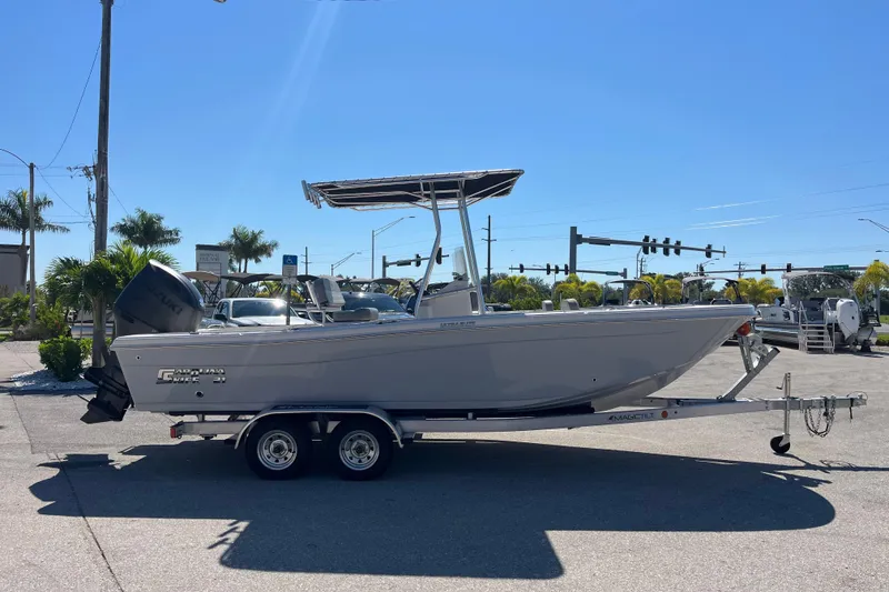 Slide: The Image of 2025 Carolina Skiff 21 Ultra Elite boat on trailer, parked outdoors under clear blue sky. - 3