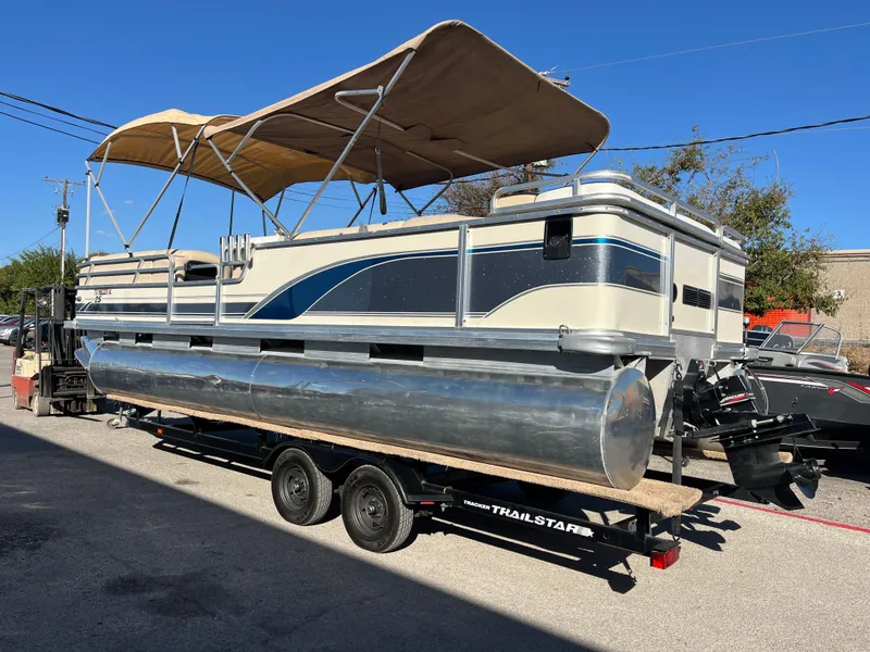 Slide: The Image of 2001 Sun Tracker PARTY BARGE 25 pontoon boat on trailer, with canopy, parked outdoors. - 14