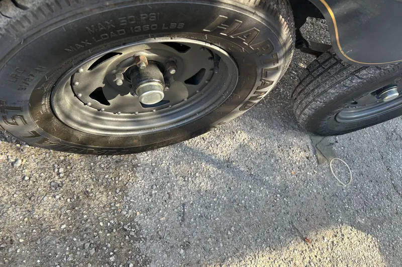 Slide: The Image of Close-up of a 2001 Sun Tracker PARTY BARGE 25 trailer wheel on gravel. - 40