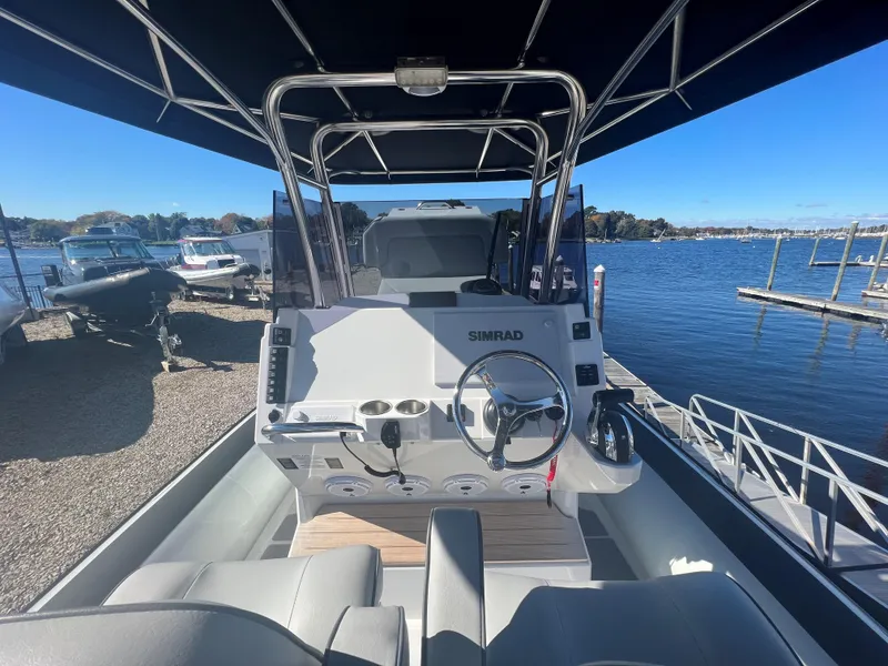 Slide: The Image of 2023 Protector 250 Chase boat interior with steering wheel, docked by a scenic waterfront. - 11