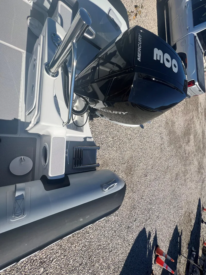 Slide: The Image of 2023 Protector 250 Chase boat with Mercury engine, parked on gravel. - 13