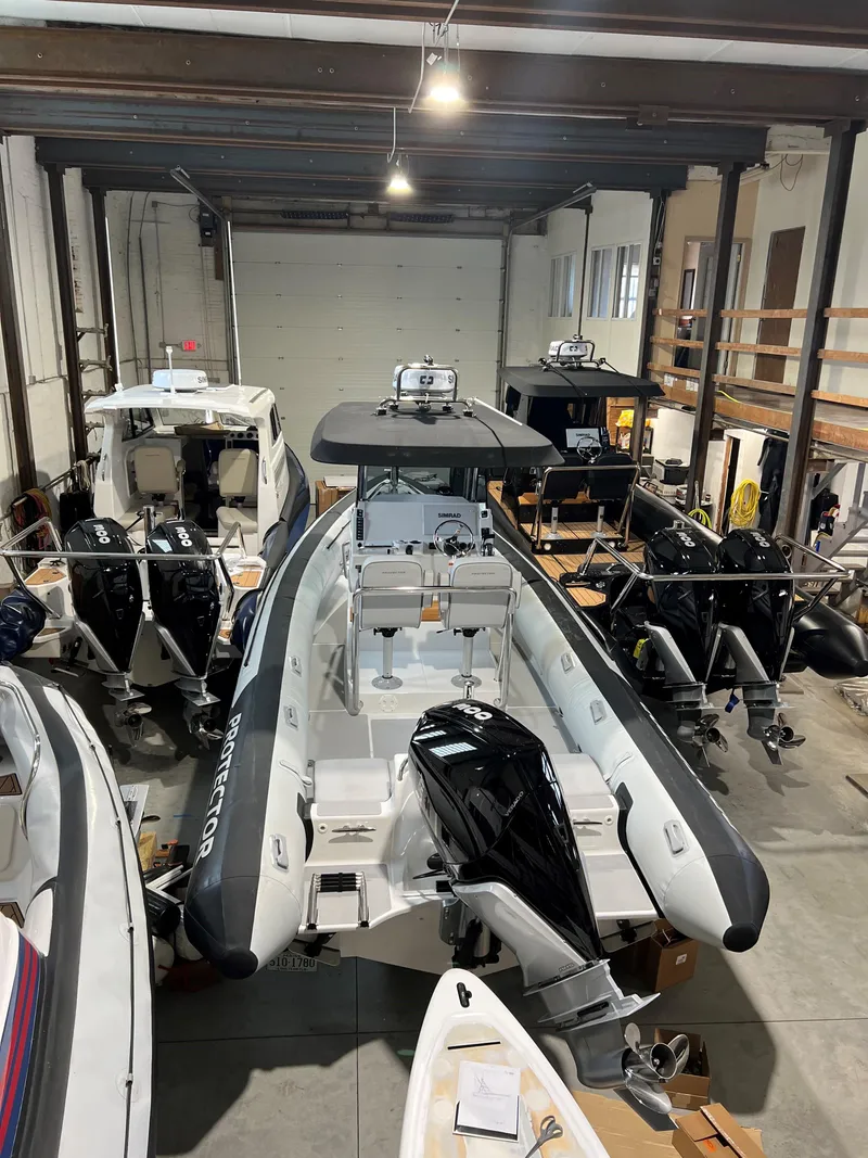 Slide: The Image of 2023 Protector 250 Chase boat in storage, featuring sleek design and powerful outboard motor. - 16