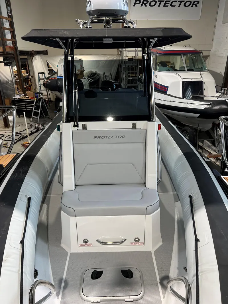 Slide: The Image of 2023 Protector 250 Chase boat interior with seating and console in a showroom. - 18
