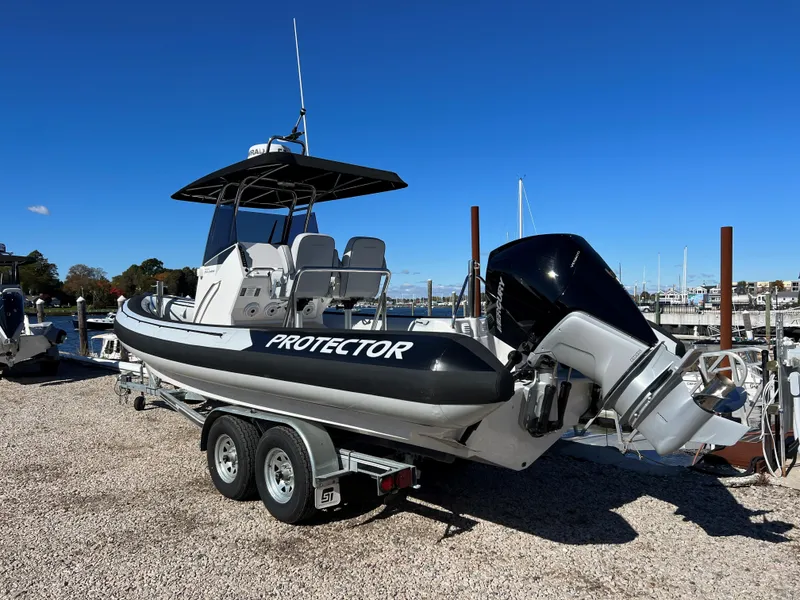 Slide: The Image of 2023 Protector 250 Chase boat on trailer, dockside, under clear blue sky. - 3