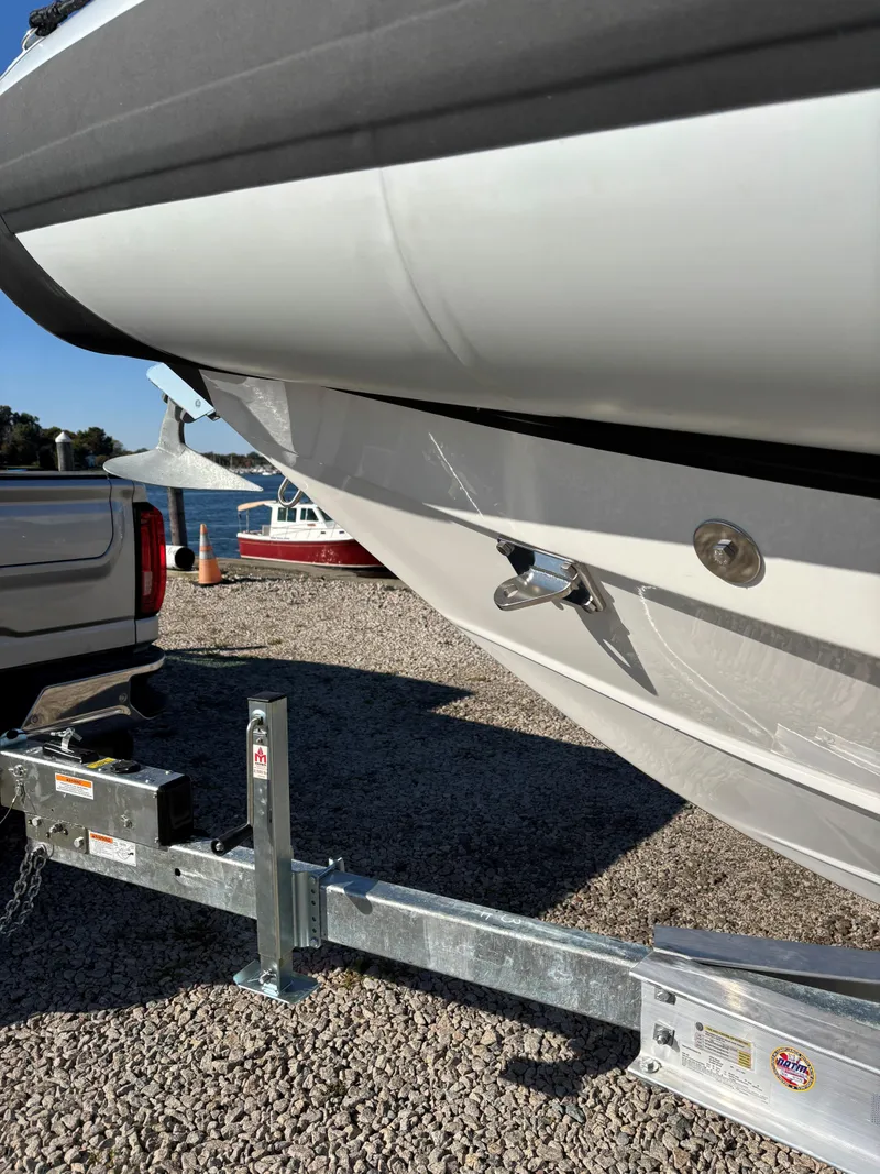 Slide: The Image of 2024 Protector 330 Chase boat on trailer, parked on gravel near water. - 10