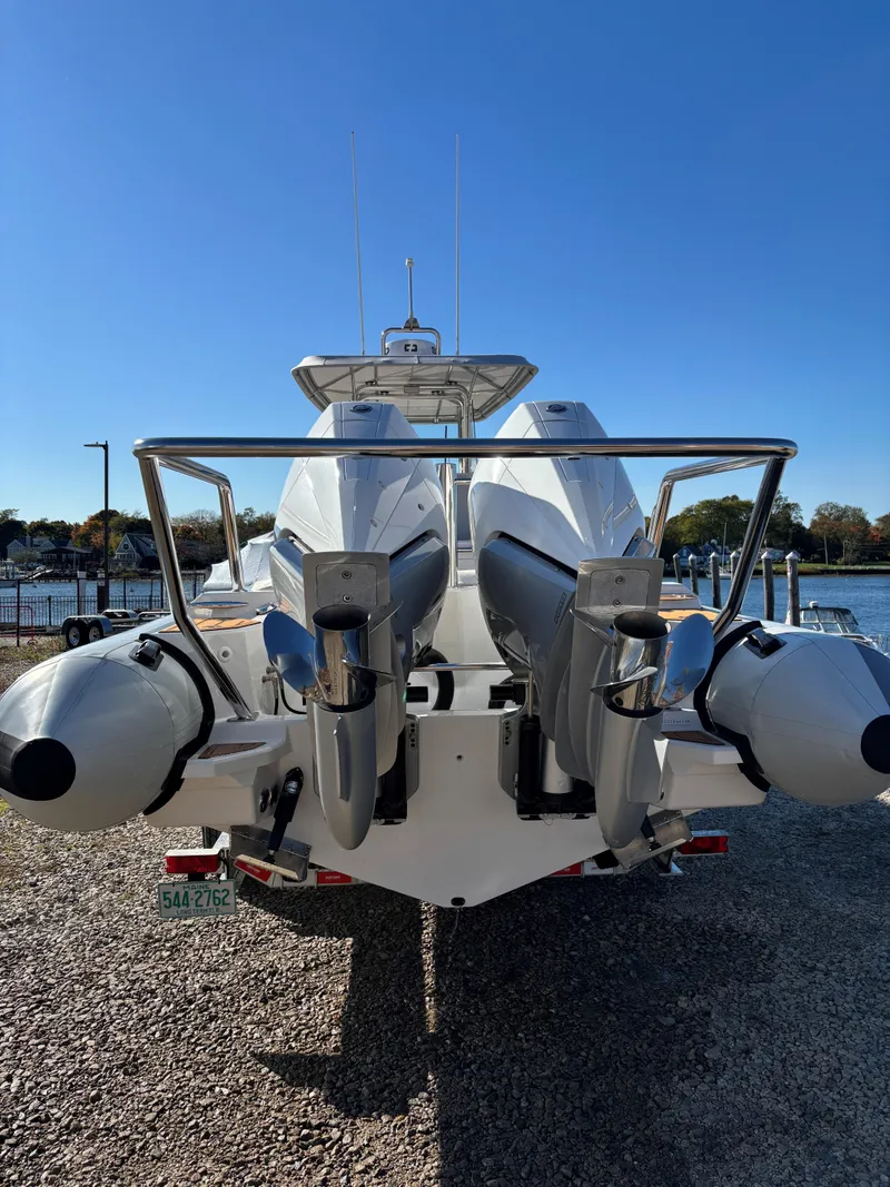 Slide: The Image of 2024 Protector 330 Chase boat with dual engines, docked on gravel, clear blue sky. - 14