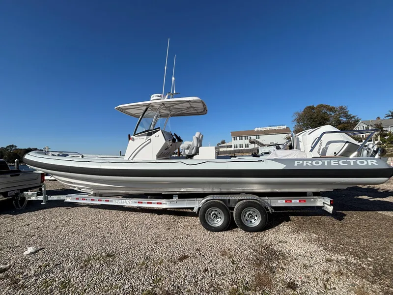 Slide: The Image of 2024 Protector 330 Chase boat on trailer under clear blue sky. - 2