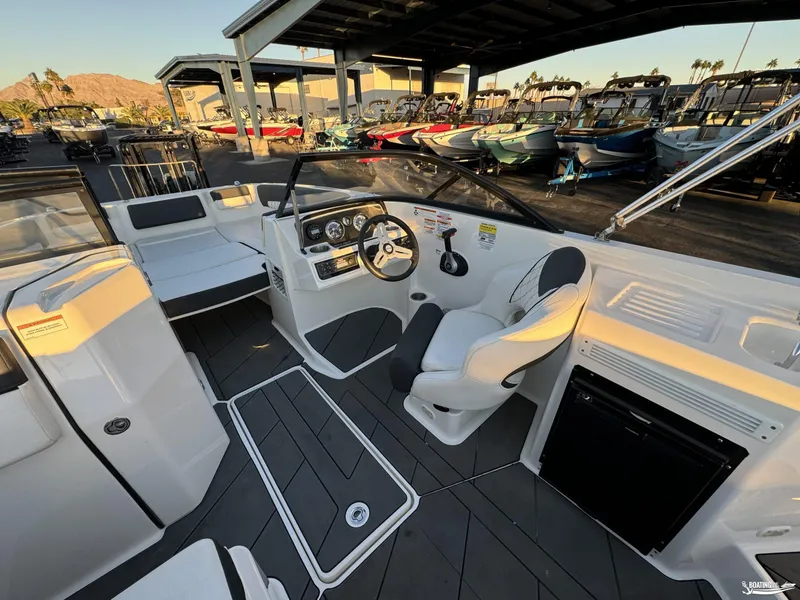Slide: The Image of 2020 Bayliner DX2250 boat interior with steering wheel and seating, docked at marina. - 7