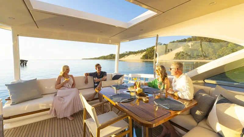 Slide: The Image of People relaxing on a 2025 Riviera 6800 Sport Yacht Platinum Edition, enjoying a scenic ocean view. - 13