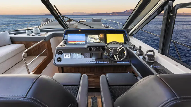 Slide: The Image of 2025 Riviera 6800 Sport Yacht Platinum Edition helm with ocean view at sunset. - 26