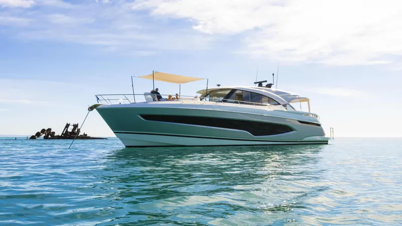 Slide: The Image of 2025 Riviera 6800 Sport Yacht Platinum Edition cruising on calm blue waters. - 5