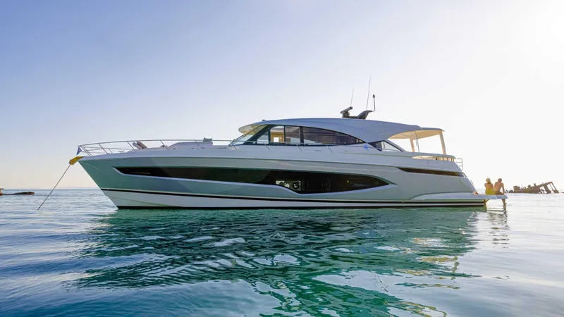 Slide: The Image of 2025 Riviera 6800 Sport Yacht Platinum Edition on calm water, side view. - 6