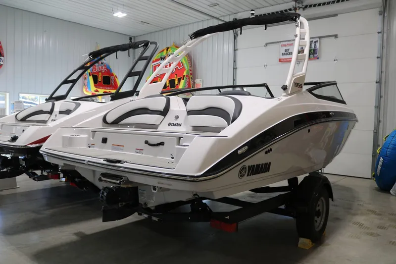 Slide: The Image of 2025 Yamaha Boats 195S in showroom, sleek design, white exterior, on trailer. - 10