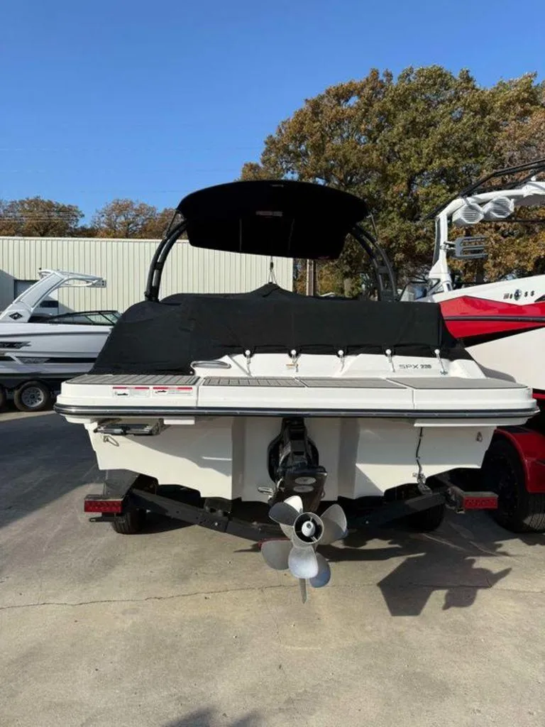 Slide: The Image of 2023 Sea Ray SPX 230 boat, rear view with cover, parked outdoors. - 11