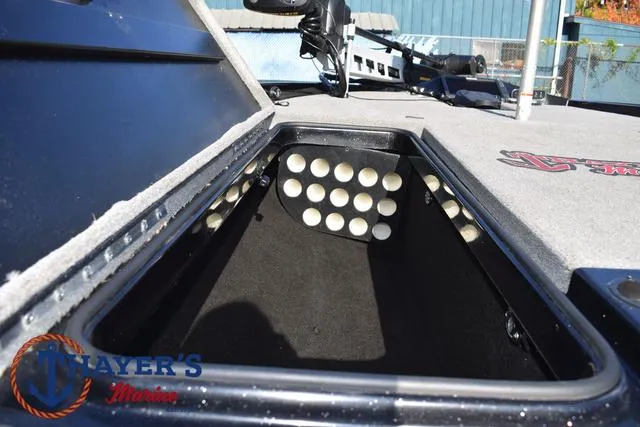 Slide: The Image of 2018 Triton 21 TrX boat storage compartment with rod holders, open lid view. - 16