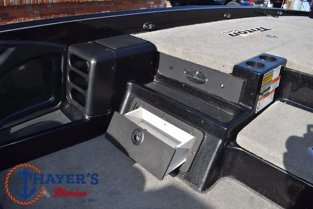 Slide: The Image of 2018 Triton 21 TrX boat interior with storage compartment and Thayer's Marine logo. - 25