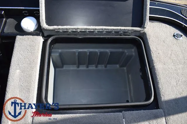 Slide: The Image of 2018 Triton 21 TrX boat storage compartment, open lid, gray interior, Thayer's Marine logo. - 35