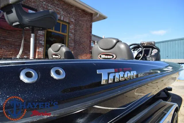 Slide: The Image of 2018 Triton 21 TrX boat with sleek black finish, parked near a brick building. - 41