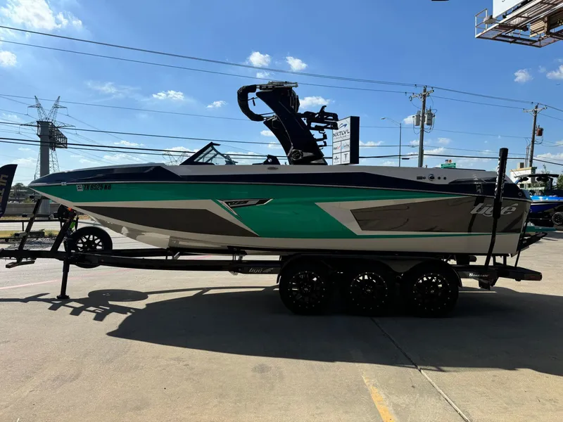 Slide: The Image of 2023 Tigé 24RZX boat on trailer, parked outdoors under a clear blue sky. - 6