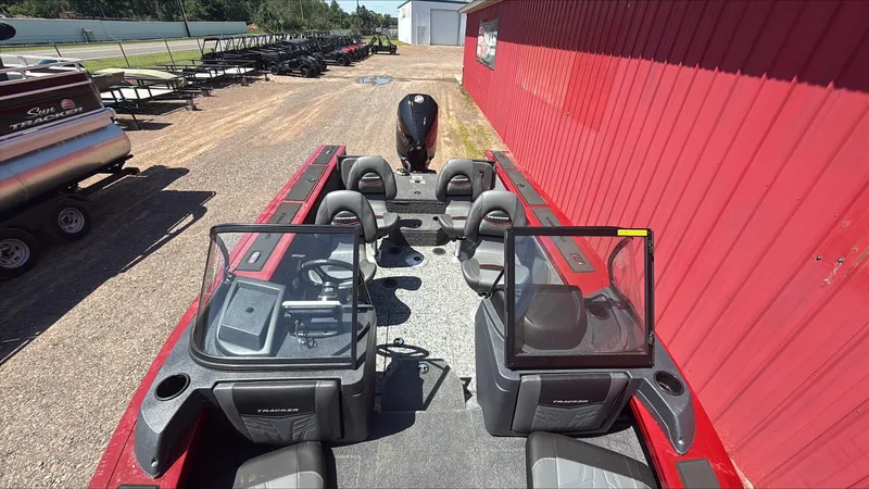 Slide: The Image of 2025 Tracker Targa V-19 Combo boat with dual consoles and seating, parked near a red building. - 3