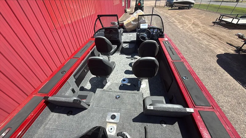 Slide: The Image of 2025 Tracker Targa V-19 Combo boat interior with seating and steering console, parked outdoors. - 5