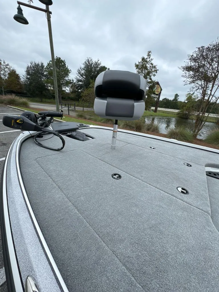 Slide: The Image of 2025 Nitro Z18 boat deck with seat and trolling motor, near a scenic lake. - 4