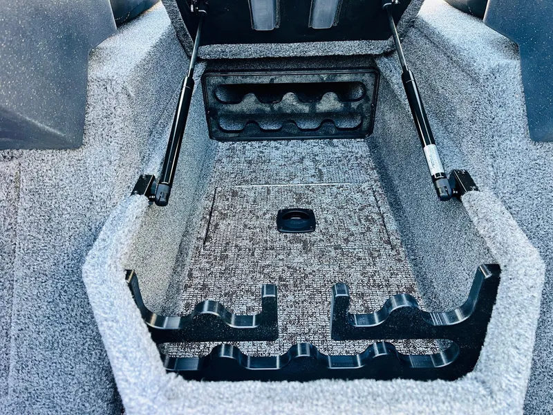 Slide: The Image of 2025 Tracker Targa V-18 Combo boat storage compartment with carpeted interior and hydraulic lift supports. - 19