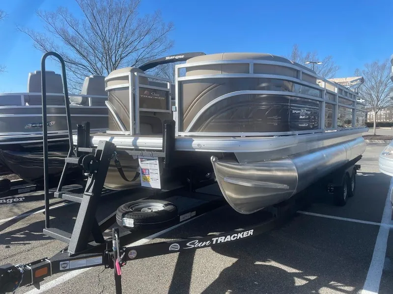 The Image of 2025 Sun Tracker SportFish 22 DLX pontoon boat on trailer, parked outdoors. - 0