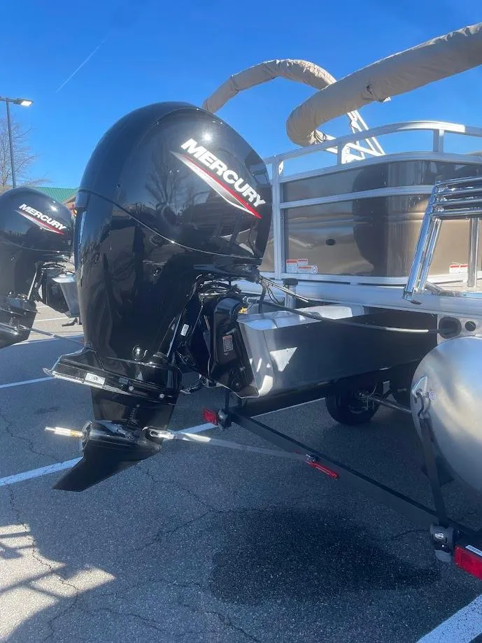 Slide: The Image of 2025 Sun Tracker SportFish 22 DLX with Mercury outboard motor in a parking lot. - 4