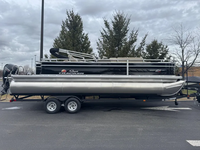 The Image of 2025 Sun Tracker Sportfish 24 XP3 pontoon boat on trailer, parked outdoors. - 0