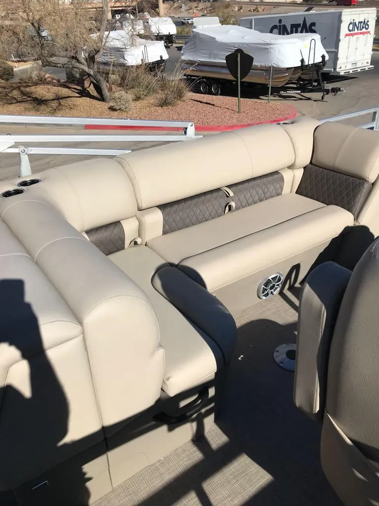 Slide: The Image of 2025 Sun Tracker Fishin' Barge 22 DLX interior with beige seating and outdoor setting. - 12