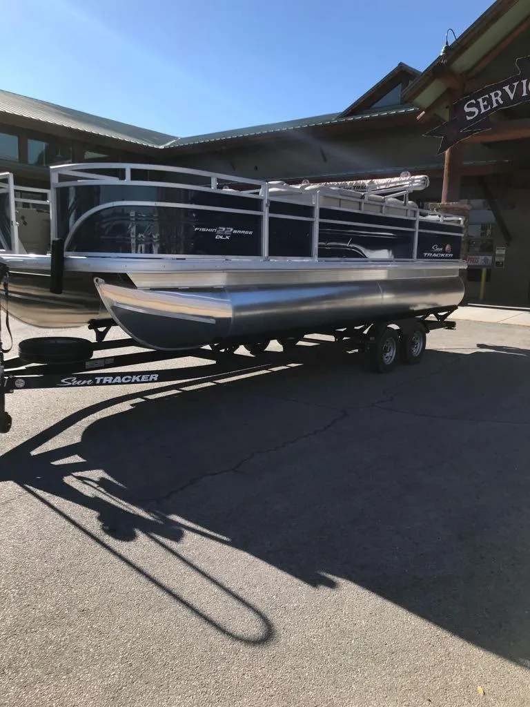Slide: The Image of 2025 Sun Tracker Fishin' Barge 22 DLX pontoon boat on trailer outside service center. - 3