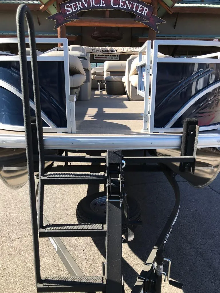 Slide: The Image of 2025 Sun Tracker Fishin' Barge 22 DLX at service center, rear view with boarding ladder. - 4