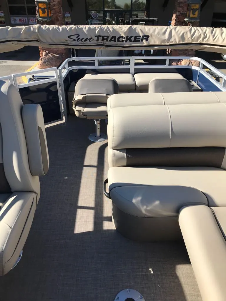 Slide: The Image of 2025 Sun Tracker Fishin' Barge 22 DLX interior with beige seating and open deck. - 8