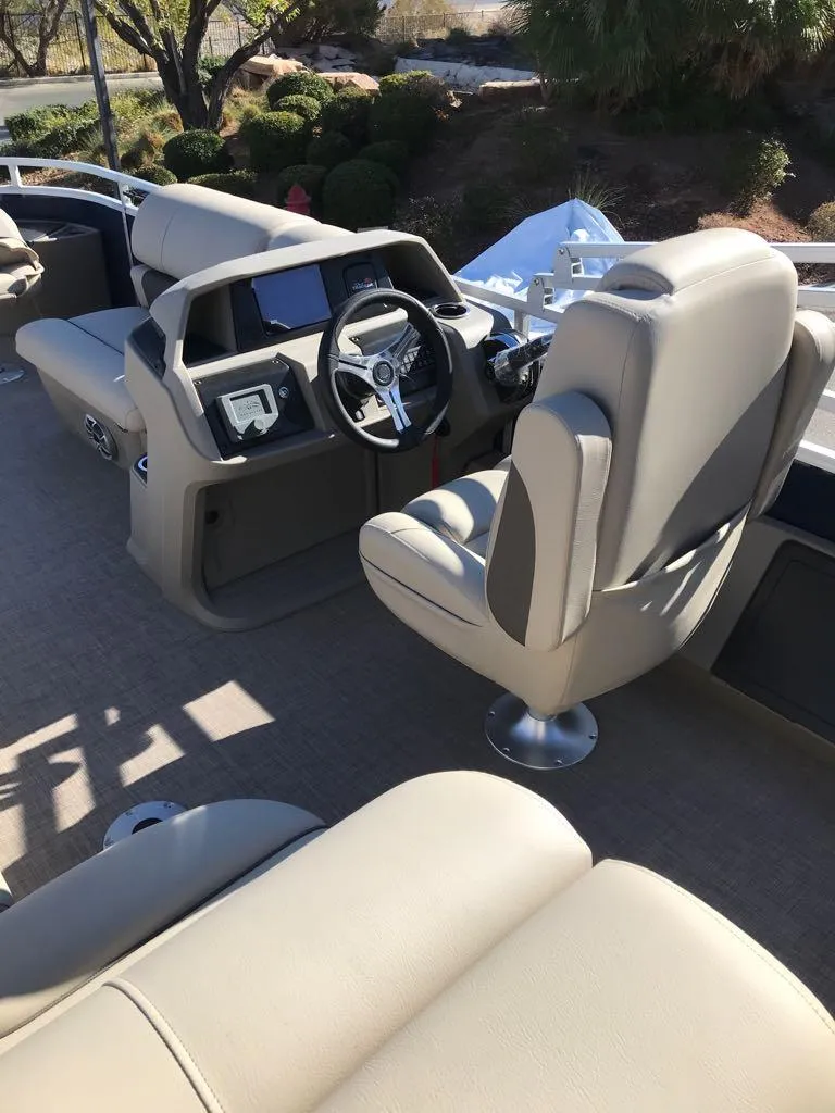 Slide: The Image of 2025 Sun Tracker Fishin' Barge 22 DLX interior with beige seating and modern dashboard. - 9