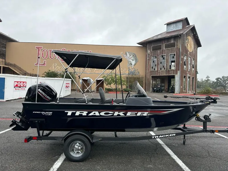Slide: The Image of 2025 Tracker Pro Guide V-16 SC boat with canopy in parking lot. - 2